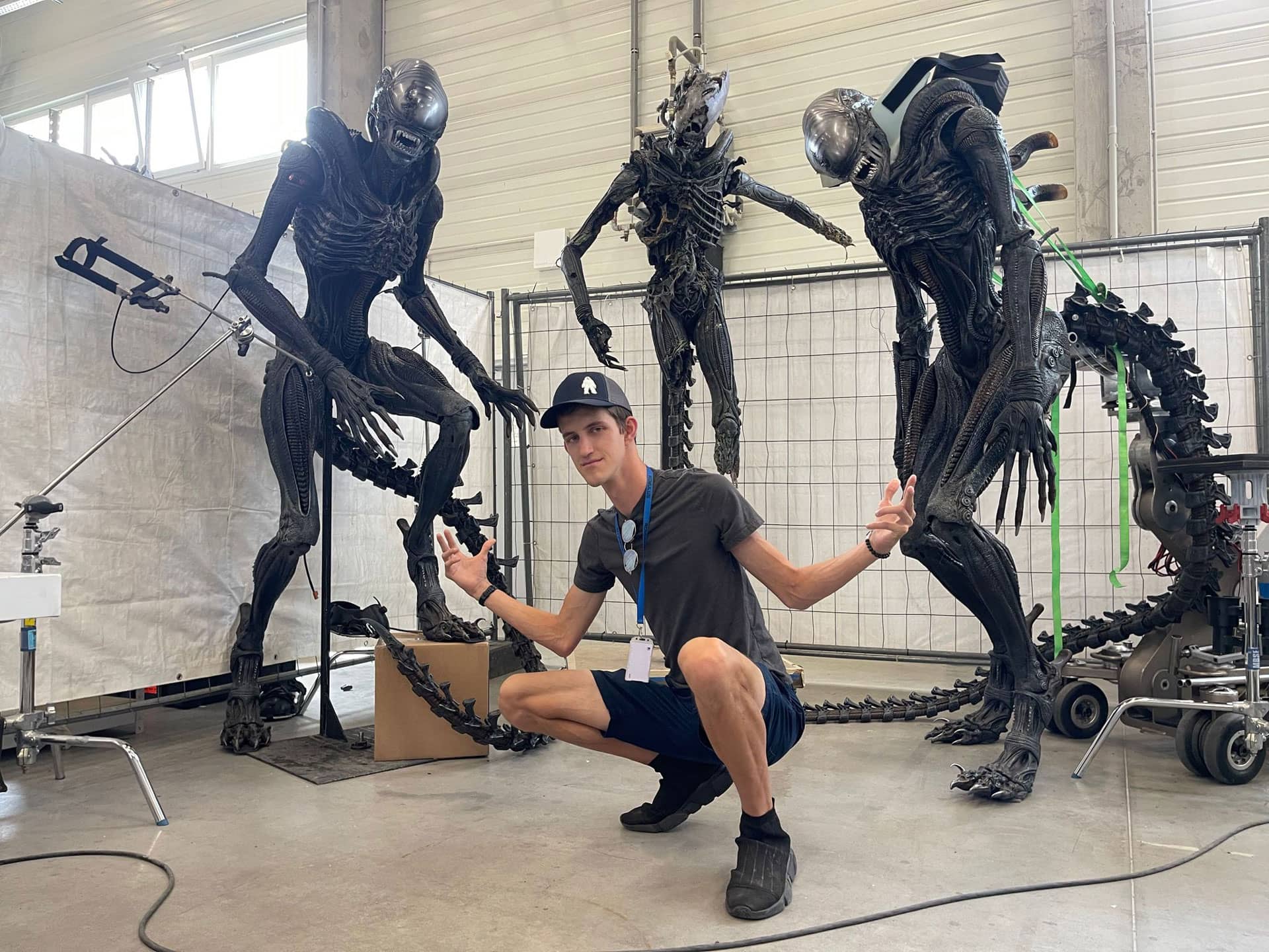 Trevor Newlin posing in front of three Xenomorphs - Legacy Effects/20th Century Studios © 2024. All Rights Reserved.